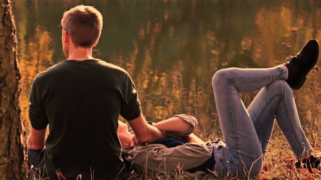A young man and woman relax in a park at sunset.